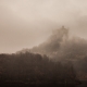 A medieval fortress rises from the fog.