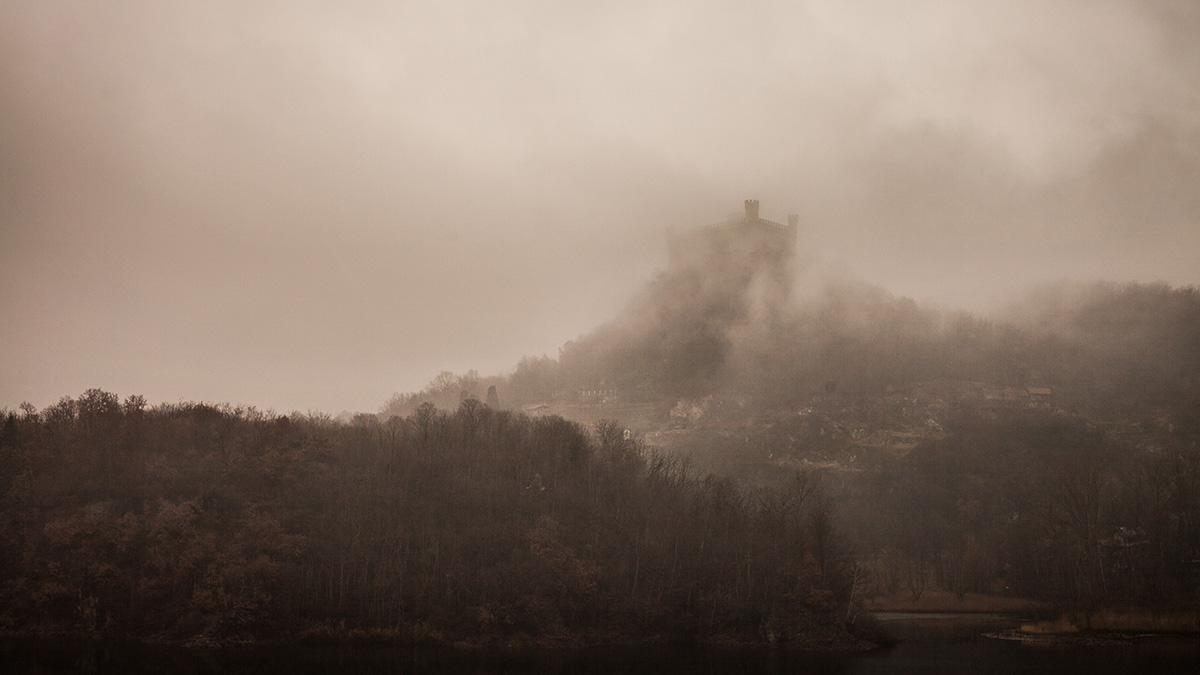 A medieval fortress rises from the fog.