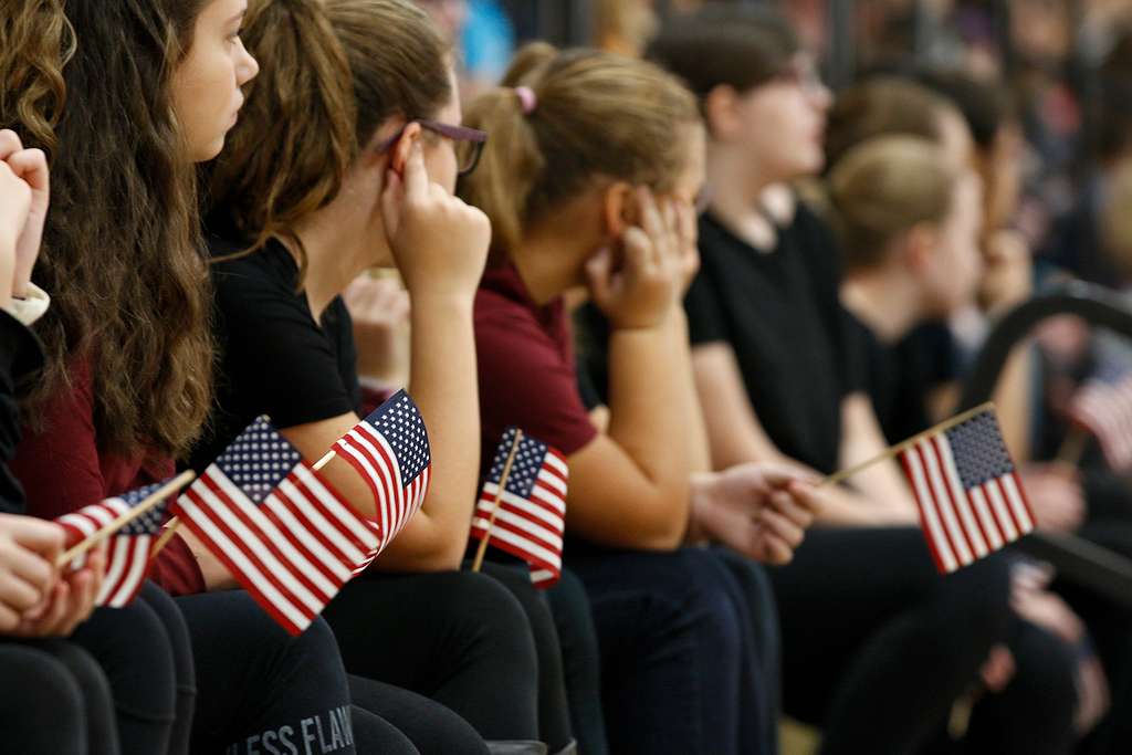 American students hold miniature flags during a school event