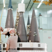 Technicians place cones on the top of the ring of an MX pathfinder missile in a preassembly building.