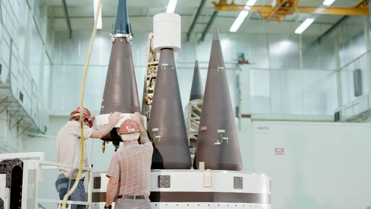 Technicians place cones on the top of the ring of an MX pathfinder missile in a preassembly building.