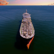 Aerial photo of large oil tanker at sea, with a colorful sunset shown on the horizon.