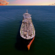 Aerial photo of large oil tanker at sea, with a colorful sunset shown on the horizon.